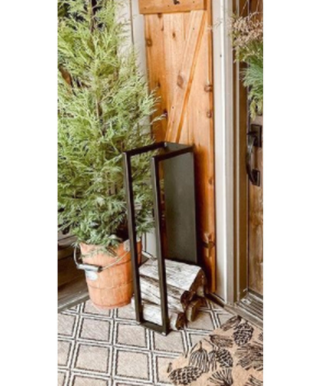 Black metal Toby Firewood Holder by Industrial Farm Co displayed on patterned tile patio with terracotta plant pot and wov...