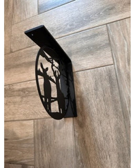Black metal L-bracket shelf support with handcrafted deer landscape cutout design mounted on light wood grain cabinet door...