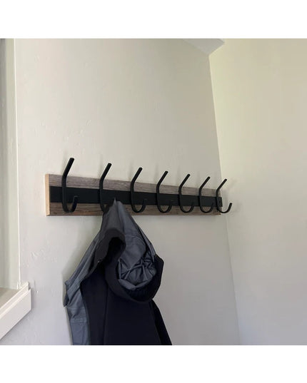 Wall-mounted Eastman Coat & Hook Rack by Industrial Farm Co with wooden base and black metal hooks holding dark jacket
